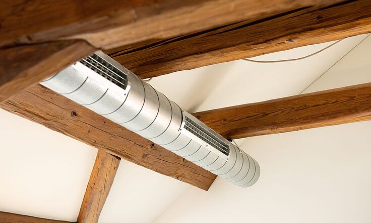 Lüftungsrohr hängt in einem Wohnzimmer unterhalb der Zimmerdecke