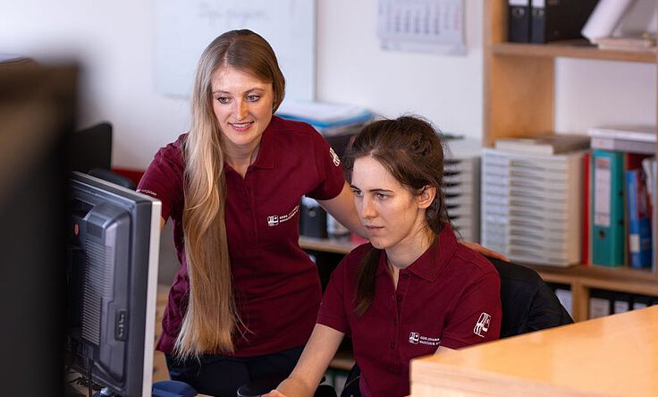 Azubis in Handwerk und Technik gesucht! Biermann-Mitarbeiterin erklärt Azubi eine Aufgabe am Computer